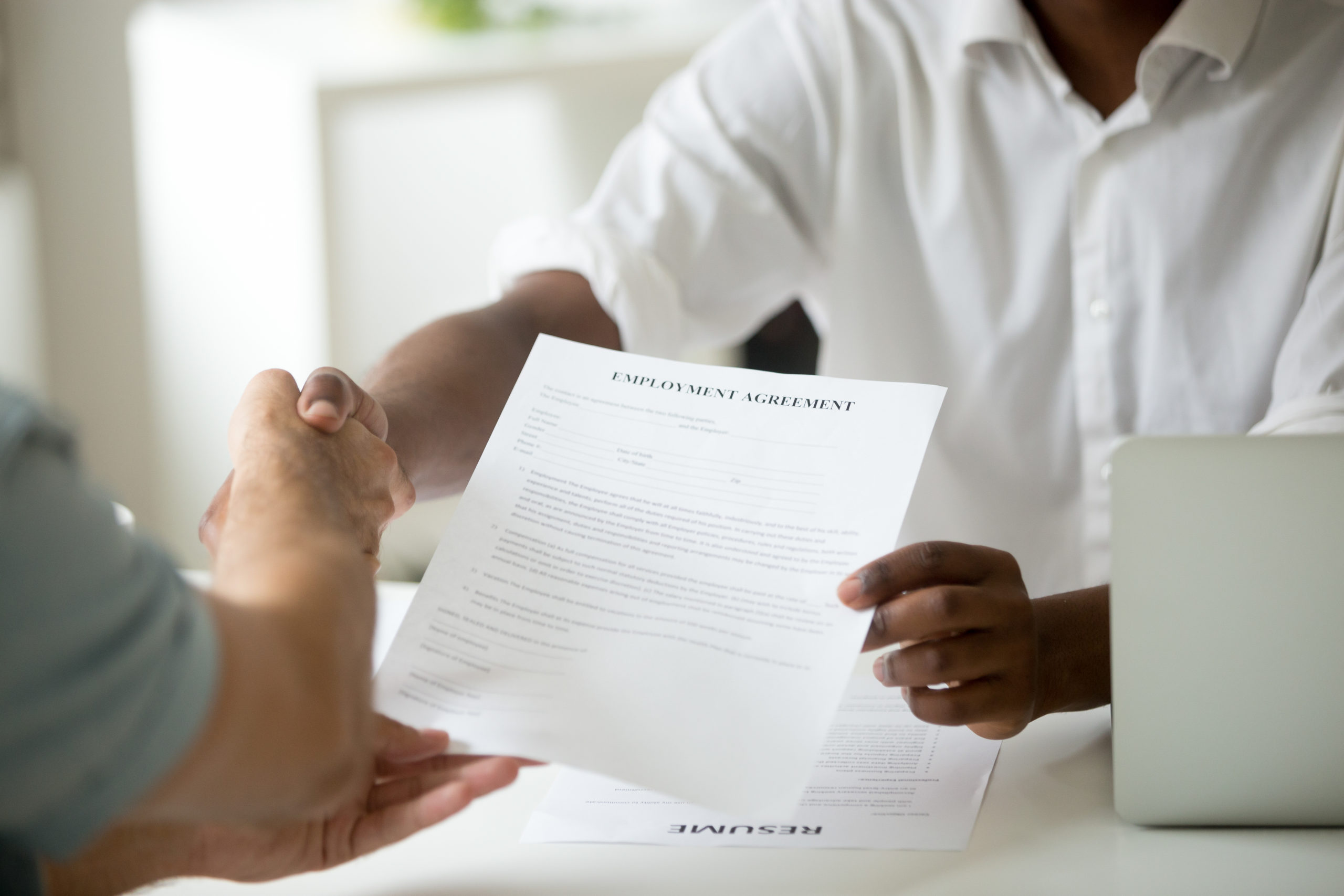 African-american employer holding employment agreement handshaki
